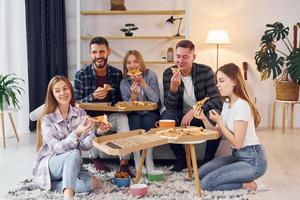 mangiare delizioso Pizza. gruppo di amici avere festa in casa insieme foto