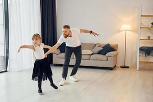 apprendimento per danza. padre con il suo poco figlia è a casa insieme foto