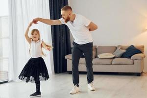 apprendimento per danza. padre con il suo poco figlia è a casa insieme foto