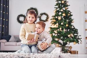 con regalo scatole. poco fratello e sorella è a Natale decorato camera insieme foto