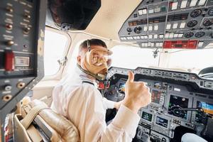 nel ossigeno maschera. pilota nel formale indossare si siede nel il cabina di pilotaggio e controlli aereo foto