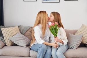 contento La madre di giorno. giovane donna con sua figlia è a casa a giorno foto