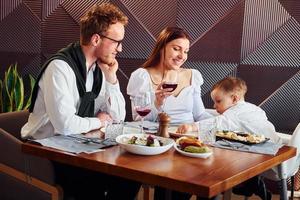 giovane tipo, donna e poco ragazzo. in casa di nuovo moderno lusso ristorante foto