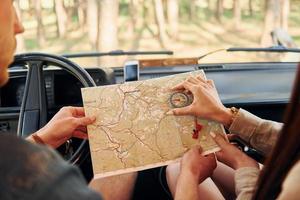 lettura il carta geografica. giovane coppia è in viaggio nel il foresta a giorno insieme foto