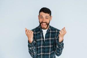 festeggiare successo. giovane uomo nel casuale Abiti in piedi in casa nel il studio foto