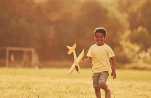 bellissimo luce del sole. africano americano ragazzo avere divertimento nel il campo a estate giorno foto