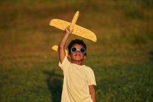 con pilota occhiali da sole. africano americano ragazzo avere divertimento nel il campo a estate giorno foto