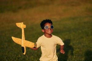 fine settimana attività. africano americano ragazzo avere divertimento nel il campo a estate giorno foto