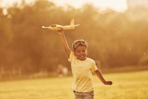 con pilota occhiali da sole. africano americano ragazzo avere divertimento nel il campo a estate giorno foto