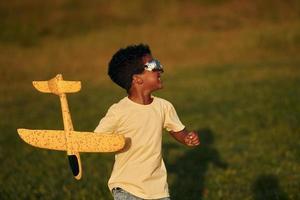 fine settimana attività. africano americano ragazzo avere divertimento nel il campo a estate giorno foto