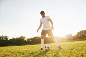 bellissimo luce del sole. giovane calcio giocatore avere formazione su il allegro campo foto