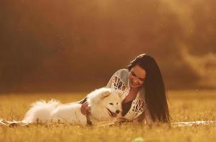 posa giù su il terra. donna con sua cane è avendo divertimento su il campo a soleggiato giorno foto