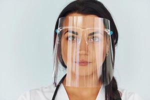 nel protettivo viso maschera. giovane femmina medico nel uniforme è in casa foto