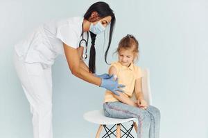 medico nel uniforme fabbricazione vaccinazione per il poco ragazza foto