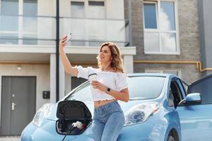 con Telefono. giovane donna nel casuale Abiti con sua elettromobile all'aperto a giorno foto