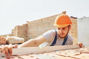 a giorno. giovane costruzione lavoratore nel uniforme è occupato a il incompiuto edificio foto