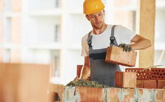 edificio processi. giovane uomo Lavorando nel uniforme a costruzione a giorno foto