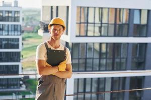 in piedi alto su. giovane uomo Lavorando nel uniforme a costruzione a giorno foto