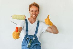 contro bianca muri. giovane uomo Lavorando nel uniforme a costruzione a giorno foto