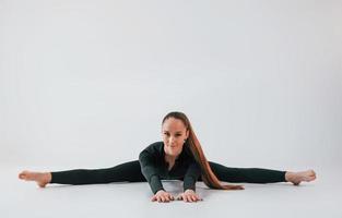 nel nero Abiti. giovane donna nel allegro Abiti fare ginnastica in casa foto