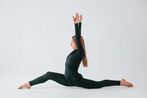 lato stirata. giovane donna nel allegro Abiti fare ginnastica in casa foto