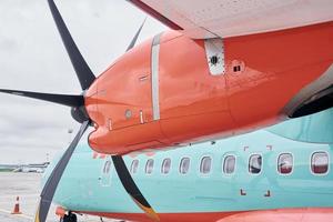 arancia e blu colorato. turboelica aereo parcheggiata su il pista di decollo a giorno foto