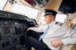 professionale lavoratore. pilota nel formale indossare si siede nel il cabina di pilotaggio e controlli aereo foto