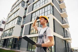 moderno città. giovane uomo Lavorando nel uniforme a costruzione a giorno foto