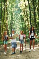 con carta geografica. bambini passeggiando nel il foresta con viaggio attrezzatura foto