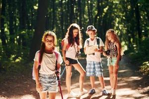 pronto per avventura. bambini passeggiando nel il foresta con viaggio attrezzatura foto
