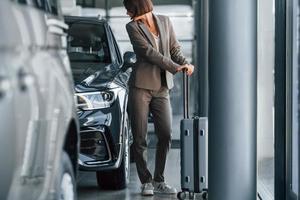 turista con bagaglio. donna è in casa vicino marca nuovo automobile in casa foto