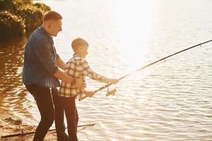 concezione di hobby. padre e figlio su pesca insieme all'aperto a estate foto