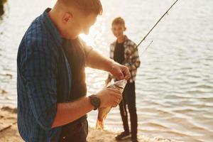 con presa. padre e figlio su pesca insieme all'aperto a estate foto