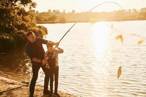 alcuni cibo per mangiare. padre e figlio su pesca insieme all'aperto a estate foto