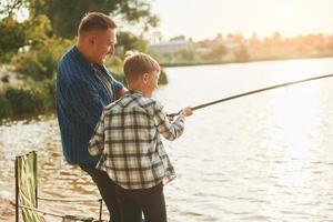 riposo e avendo divertimento. padre e figlio su pesca insieme all'aperto a estate foto