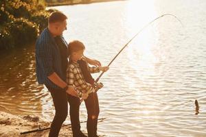 concezione di hobby. padre e figlio su pesca insieme all'aperto a estate foto