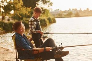 soleggiato tempo atmosferico. padre e figlio su pesca insieme all'aperto a estate foto