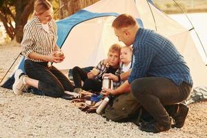 attivo tempo spesa. famiglia di madre, padre e bambini è su il campeggio foto