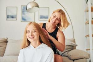 genitore porzione con capelli. femmina adolescente con sua madre è a casa a giorno foto