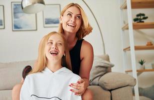 positivo emozioni. femmina adolescente con sua madre è a casa a giorno foto