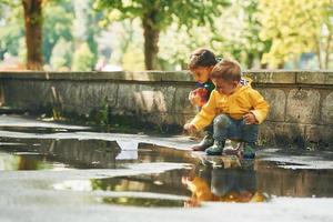 nel il pozzanghera. bambini avendo divertimento all'aperto nel il parco dopo il pioggia foto