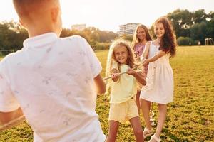 avendo divertimento. gruppo di contento bambini è all'aperto su il allegro campo a giorno foto