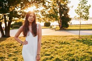 nel bianca vestire. donna in piedi nel il autunno parco. bellissimo luce del sole foto