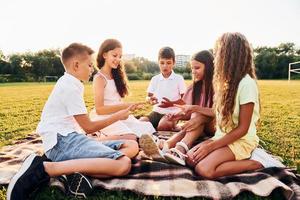 giocando Giochi. gruppo di contento bambini è all'aperto su il allegro campo a giorno foto