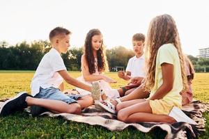 giocando Giochi. gruppo di contento bambini è all'aperto su il allegro campo a giorno foto