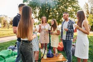 in piedi vicino narghilè. gruppo di giovane persone avere un' festa nel il parco a estate giorno foto