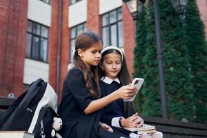 seduta insieme. Due studentesse è al di fuori vicino scuola edificio foto