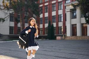 avendo un' camminare. scolara è al di fuori vicino scuola edificio foto