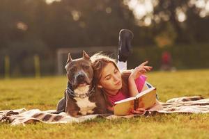 lettura il libro. donna nel casuale Abiti è con fossa Toro all'aperto foto