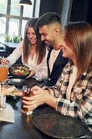 a giorno. gruppo di giovane amici seduta insieme nel bar con birra foto